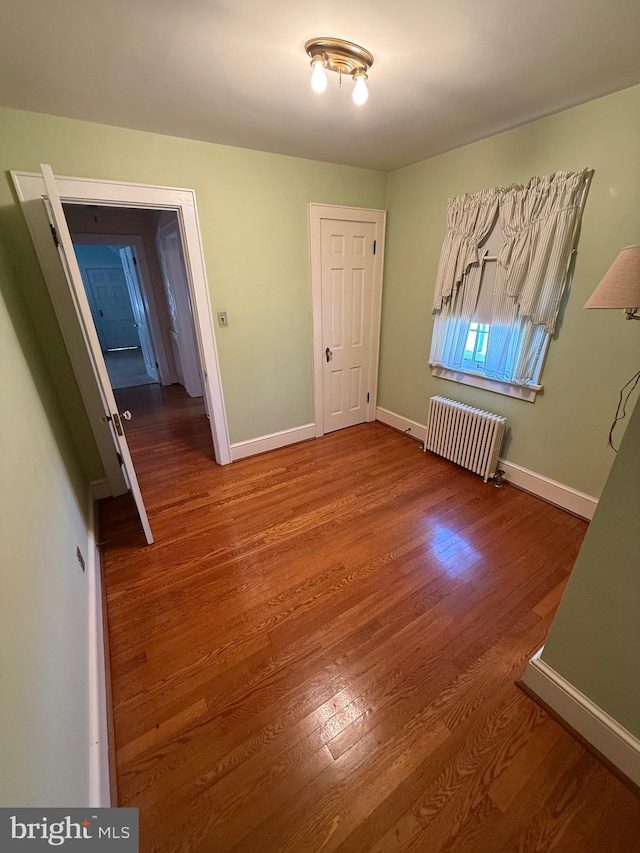 interior space with radiator, baseboards, and wood finished floors