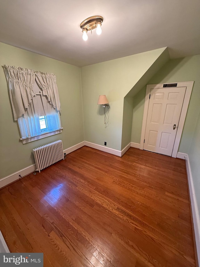 additional living space featuring radiator heating unit, wood finished floors, and baseboards