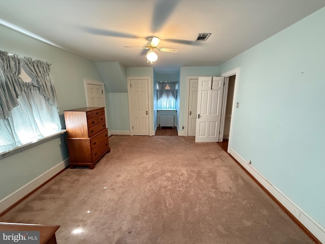 unfurnished bedroom featuring visible vents, baseboards, a ceiling fan, radiator heating unit, and carpet floors