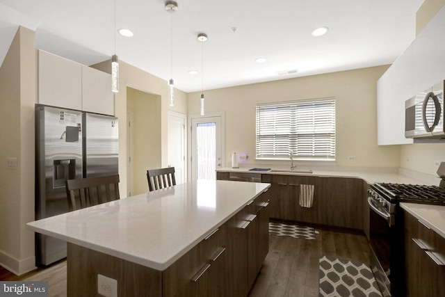 kitchen with light countertops, dark wood-style floors, appliances with stainless steel finishes, and a sink