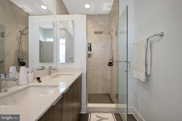 bathroom with a sink, baseboards, double vanity, and a shower stall