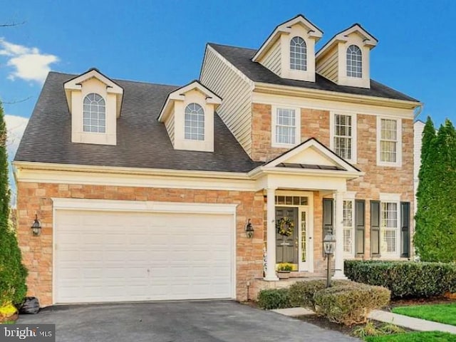 view of front of house with driveway, stone siding, and an attached garage