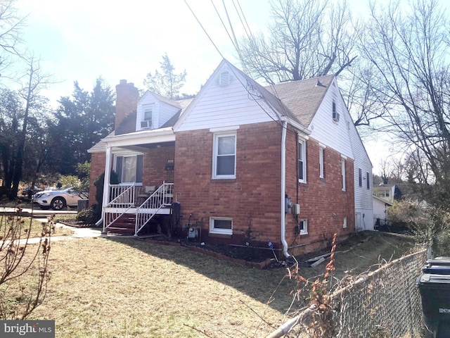 view of front of property with a front yard, brick siding, and a chimney