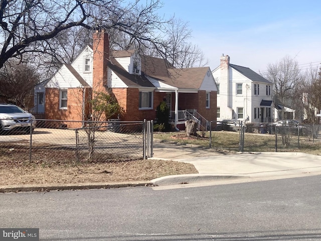 cape cod home featuring a fenced front yard, brick siding, and a chimney