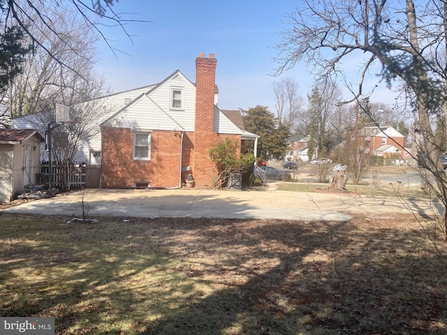 rear view of house featuring brick siding, fence, crawl space, a chimney, and a patio area