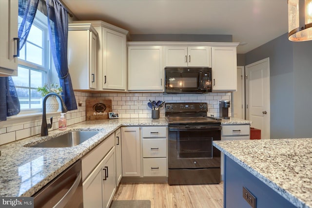 kitchen with light stone counters, light wood finished floors, backsplash, a sink, and black appliances