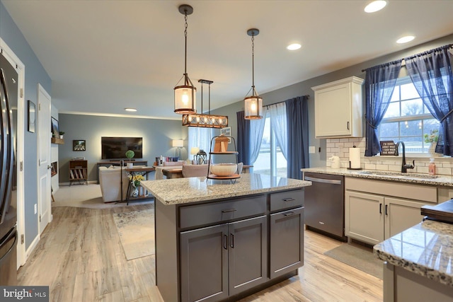 kitchen with light wood-style flooring, decorative backsplash, a sink, light stone countertops, and dishwasher