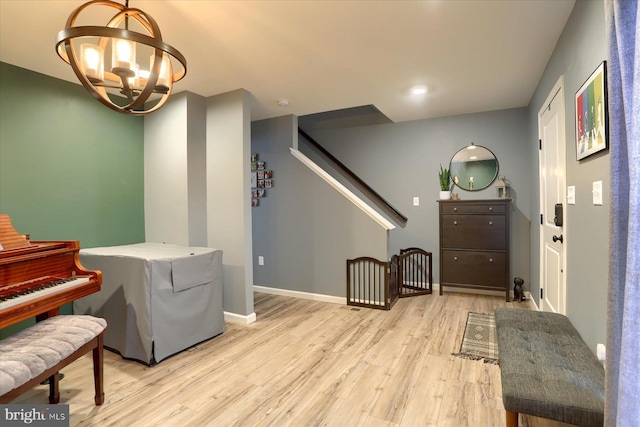 sitting room with stairway, baseboards, a chandelier, and wood finished floors