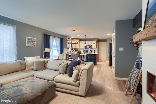 living room with light wood-style floors, recessed lighting, and baseboards