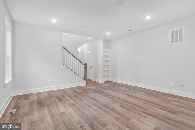 interior space with light wood-style flooring, stairs, visible vents, and baseboards