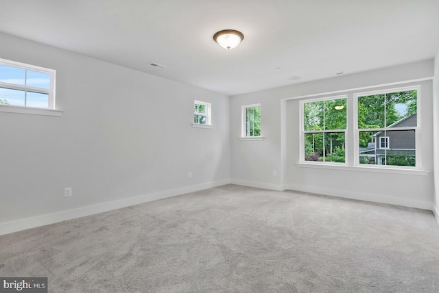 carpeted empty room featuring visible vents and baseboards