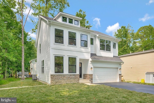 view of front of property featuring a garage, central AC unit, stone siding, aphalt driveway, and a front yard