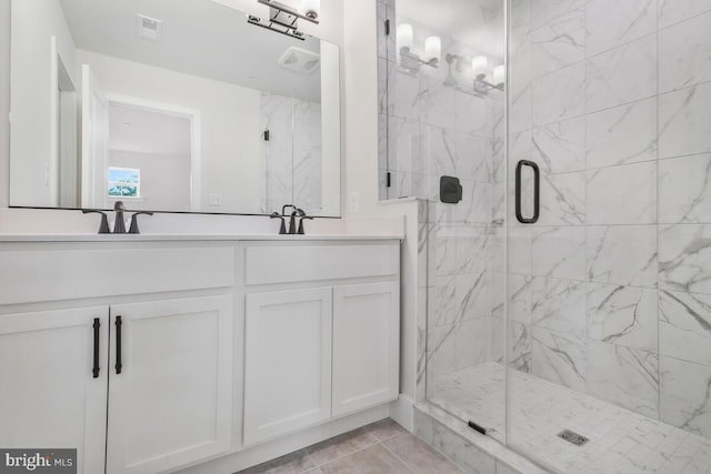 bathroom featuring double vanity, a marble finish shower, and a sink