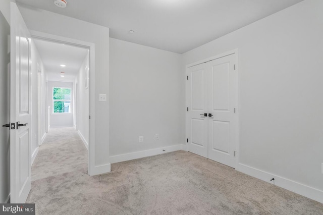 unfurnished bedroom with a closet, carpet flooring, and baseboards