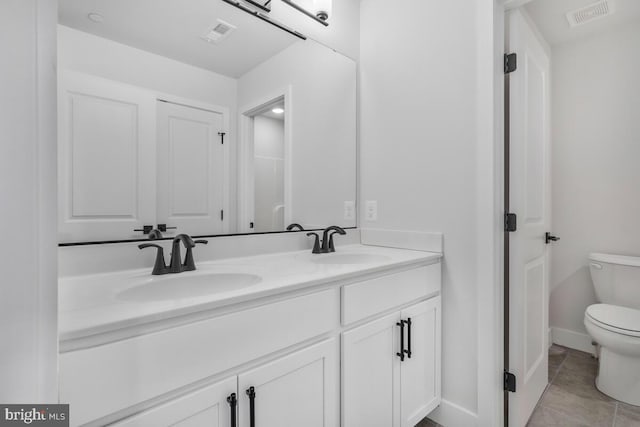 bathroom featuring visible vents, double vanity, a sink, and toilet