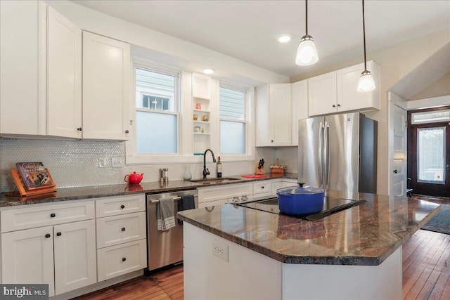 kitchen featuring a kitchen island, a sink, white cabinetry, appliances with stainless steel finishes, and dark stone countertops