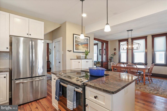 kitchen featuring decorative light fixtures, appliances with stainless steel finishes, light wood-style flooring, and white cabinets