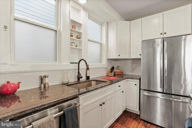 kitchen with a sink, white cabinetry, appliances with stainless steel finishes, tasteful backsplash, and dark stone countertops