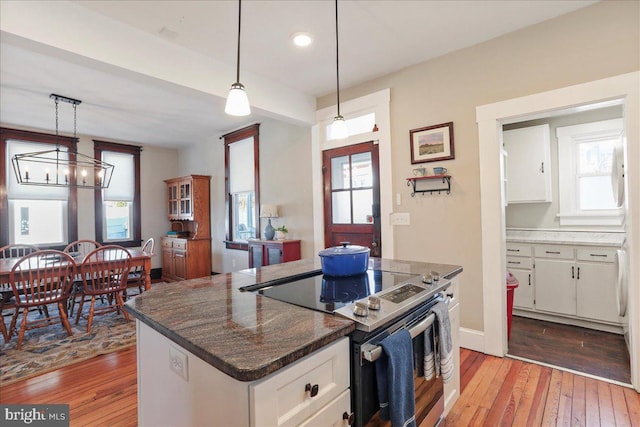 kitchen with stainless steel range with electric stovetop, white cabinets, and light wood-style floors