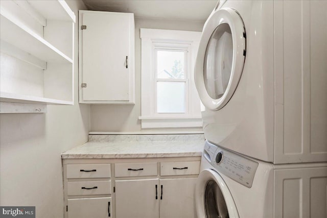 washroom with cabinet space and stacked washer and clothes dryer