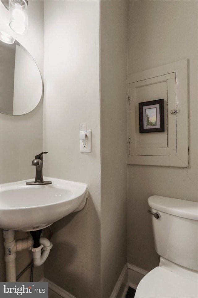 bathroom featuring toilet, baseboards, and a sink