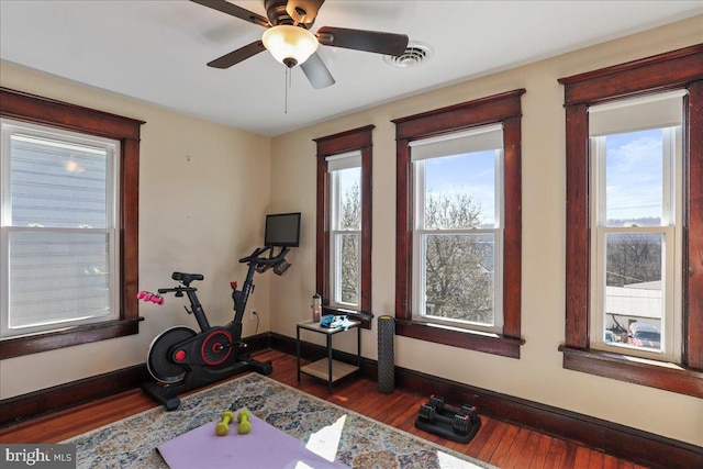 exercise room with a ceiling fan, baseboards, visible vents, and wood finished floors