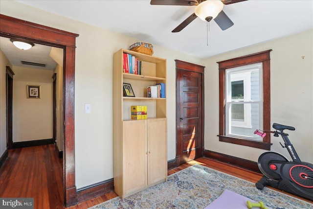 exercise area featuring ceiling fan, wood finished floors, visible vents, and baseboards