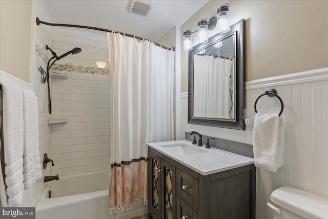 bathroom with visible vents, wainscoting, toilet, shower / tub combo with curtain, and vanity