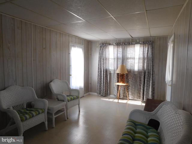 sitting room featuring a paneled ceiling and wooden walls