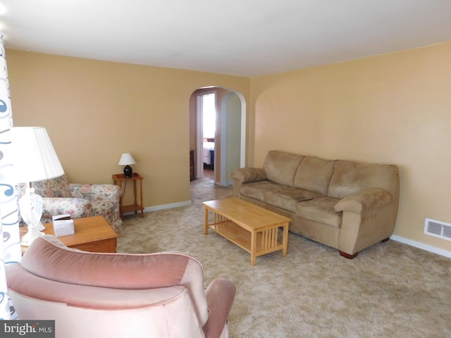 carpeted living area with visible vents, arched walkways, and baseboards