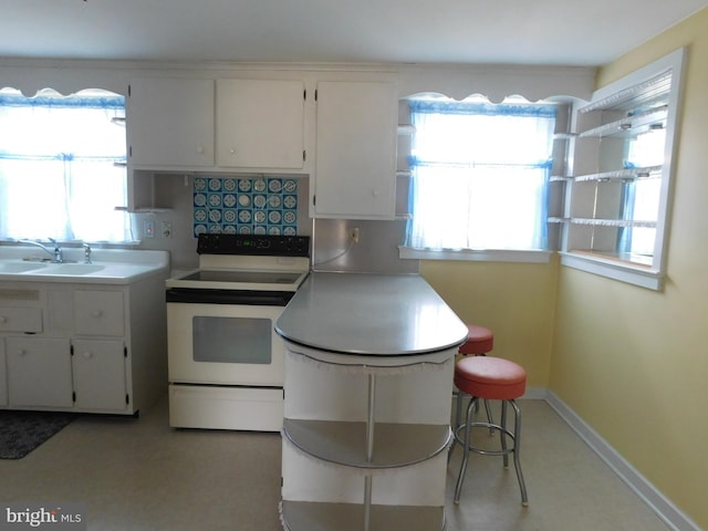 kitchen featuring white cabinetry, a sink, electric range, and baseboards