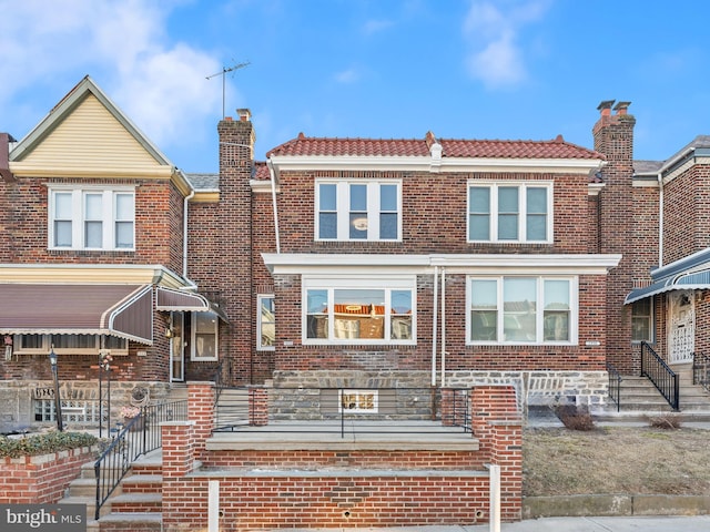 view of property featuring a tile roof and brick siding