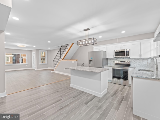 kitchen with a sink, white cabinets, appliances with stainless steel finishes, backsplash, and wood tiled floor