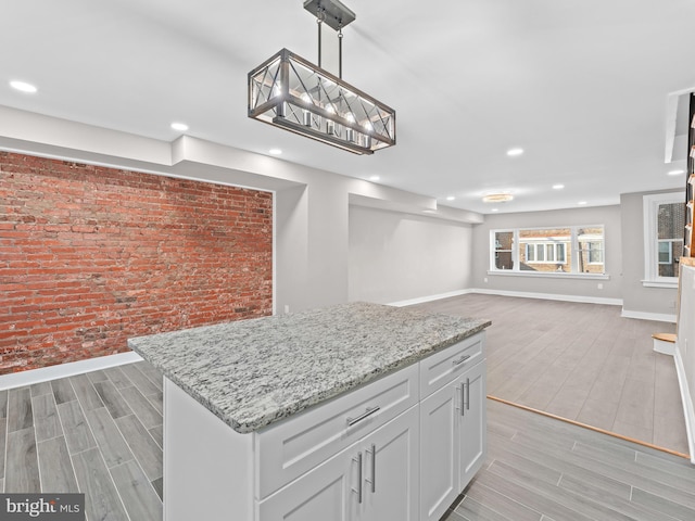 kitchen with wood tiled floor, a center island, baseboards, and brick wall