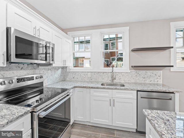 kitchen with open shelves, stainless steel appliances, tasteful backsplash, white cabinetry, and a sink