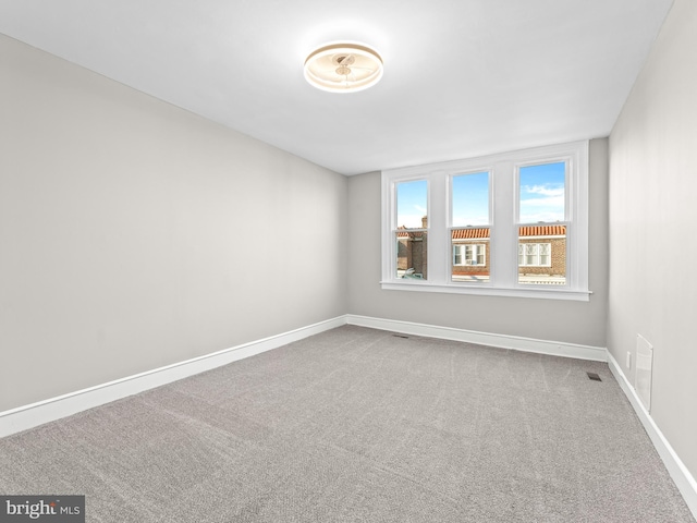 carpeted empty room featuring visible vents and baseboards