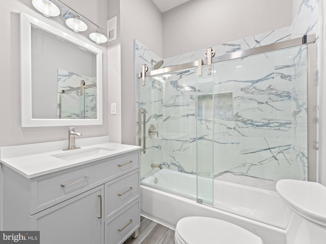 bathroom featuring visible vents, toilet, enclosed tub / shower combo, vanity, and wood finished floors