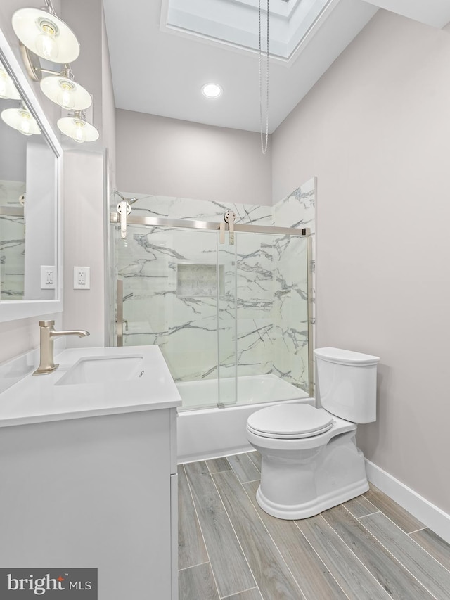 full bathroom featuring toilet, wood tiled floor, combined bath / shower with glass door, vanity, and baseboards