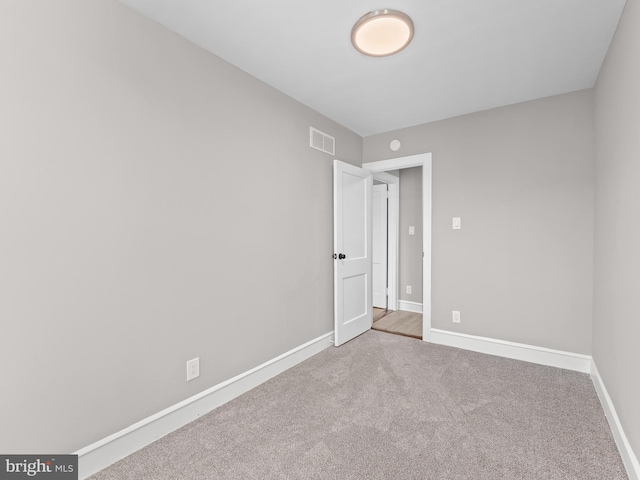 empty room with carpet floors, visible vents, and baseboards