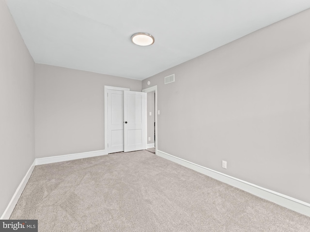 unfurnished room featuring carpet, visible vents, and baseboards