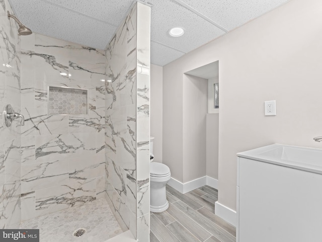 bathroom with baseboards, a marble finish shower, toilet, and wood tiled floor