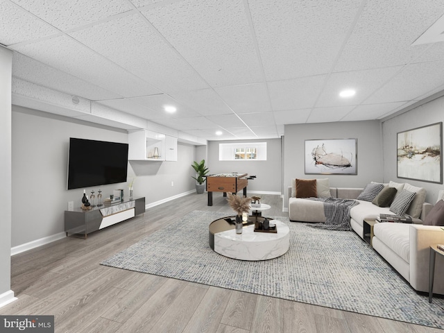 living area featuring recessed lighting, a drop ceiling, baseboards, and wood finished floors