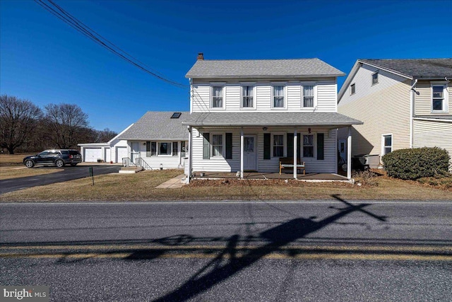 view of front of property with an outbuilding, a porch, a garage, roof with shingles, and a chimney