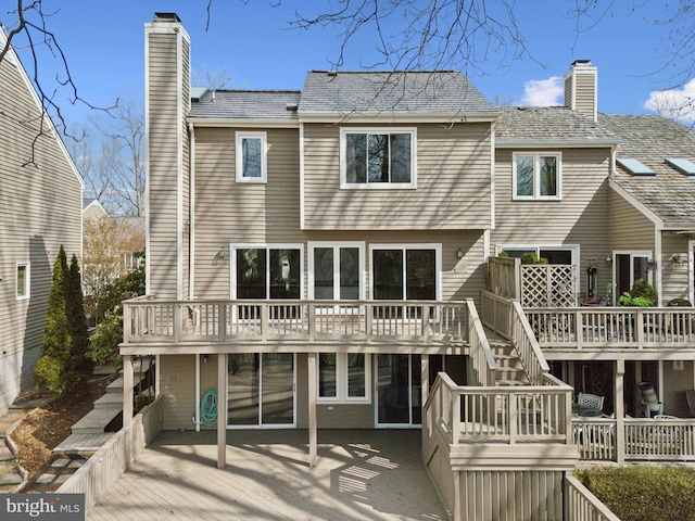 back of house with a deck, stairway, and a chimney