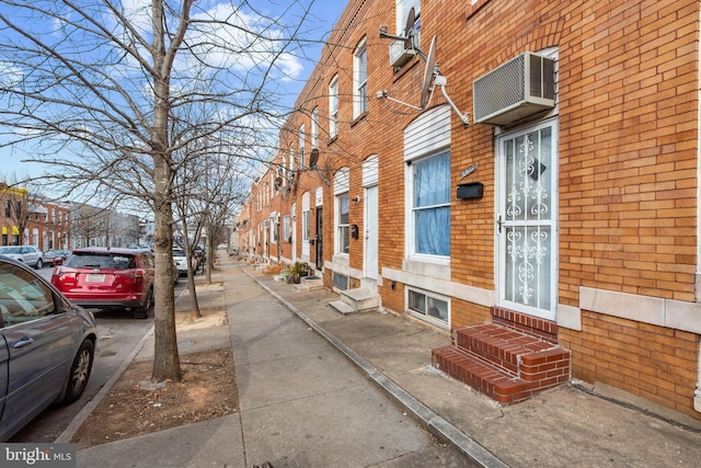 view of home's exterior featuring entry steps, a residential view, an AC wall unit, and brick siding