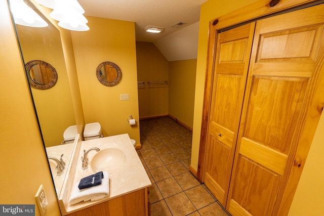 bathroom featuring visible vents, a closet, tile patterned flooring, vanity, and vaulted ceiling