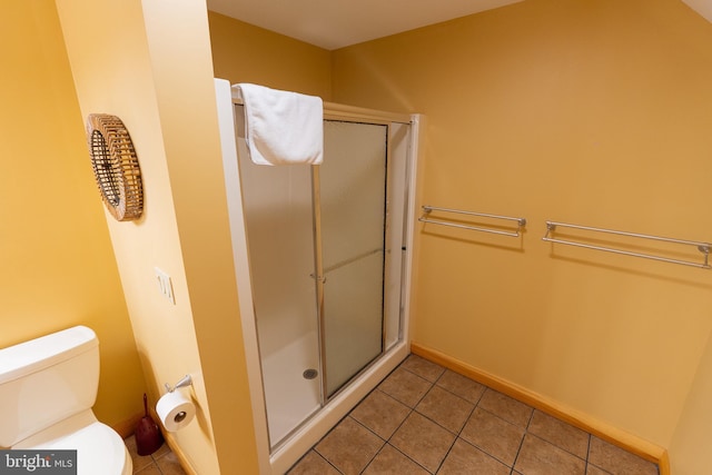 bathroom with tile patterned floors, baseboards, toilet, and a stall shower