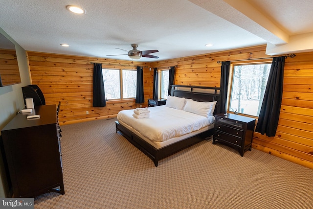 bedroom featuring recessed lighting, light colored carpet, wood walls, and a textured ceiling