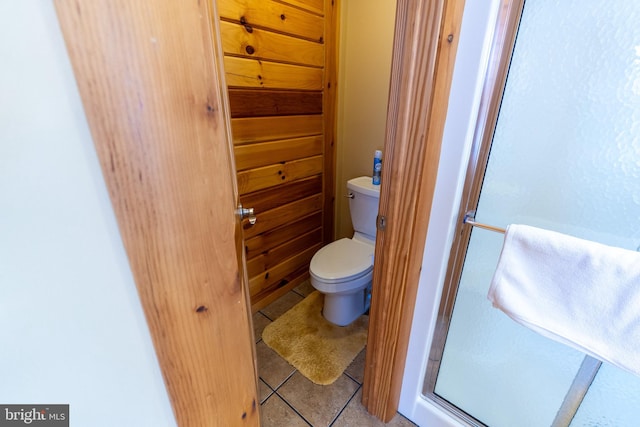 bathroom with tile patterned floors, toilet, a stall shower, and a sink