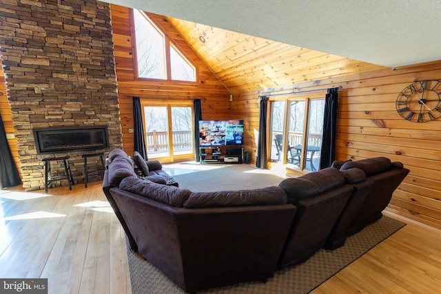 living area with light wood-type flooring, a textured ceiling, wood walls, and a fireplace